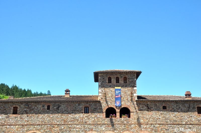 Castello Di Amorosa: каменная башня с флагом 10-й годовщины